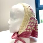 bonnet a nouer crochet Rosalie écru et rose présenté sur un mannequin blanc
