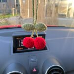 suspension cerise crochet rouge et verte accrochée au rétroviseur intérieur d’une voiture