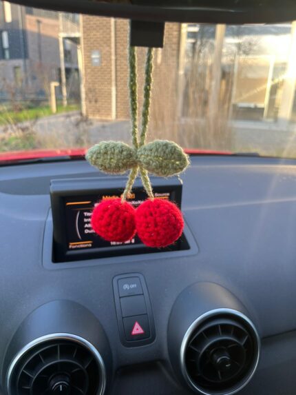 suspension cerise crochet rouge et verte accrochée au rétroviseur intérieur d’une voiture