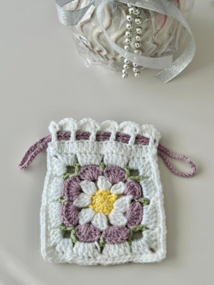 Pochette fleur au crochet blanche avec marguerite mauve, jaune et verte et fermeture par cordons