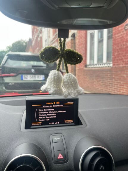 muguet crochet retroviseur avec deux fleurs blanches et feuilles vertes suspendu dans une voiture