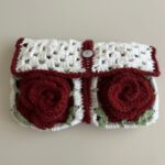 Protège-livre de poche au crochet blanc avec deux roses bordeaux en relief et fermeture à bouton